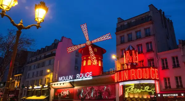 Le Moulin Rouge illuminé la nuit. La durée du spectacle est une question que beaucoup se posent avant de venir admirer ce lieu emblématique.