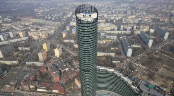 Widok z lotu ptaka na Sky Tower we Wrocławiu, otoczony blokami mieszkalnymi i miejskim krajobrazem.