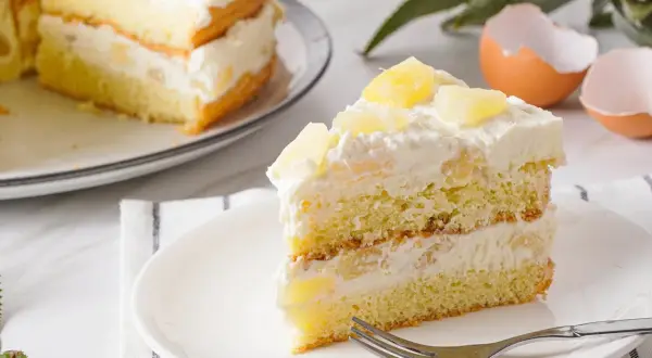 Ein saftiges Stück Ananas Torte mit Sahne und Ananasstücken, bereit zum Genießen.