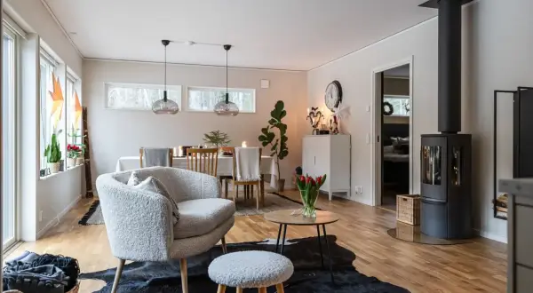 Ett mysigt vardagsrum med en fluffig fåtölj, en kamin och en matplats.