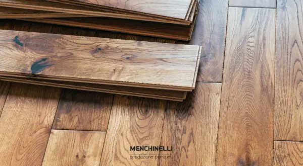 Pezzi di parquet in legno di rovere impilati, pronti per la finitura. La venatura naturale del legno è ben visibile.