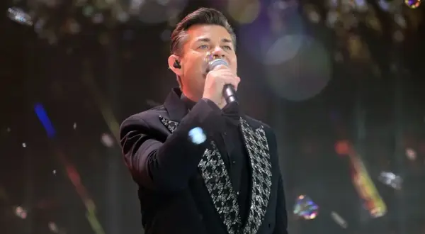Artysta w czarnym fraku z błyszczącymi zdobieniami śpiewa, a jego zielone oczy zdają się mówić: "akcent przez twe oczy zielone tekst".