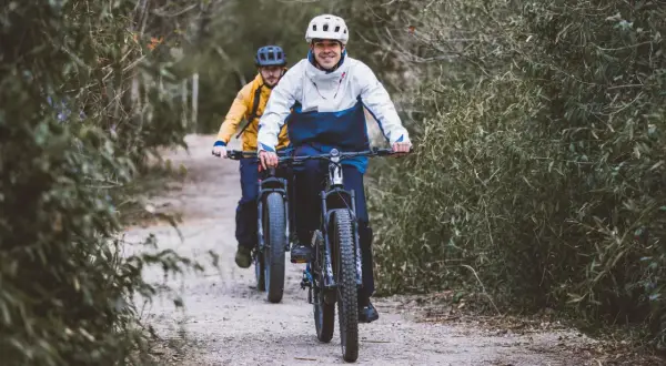 Dwóch rowerzystów pokonuje trasę przez las, ciesząc się aktywnością na świeżym powietrzu.