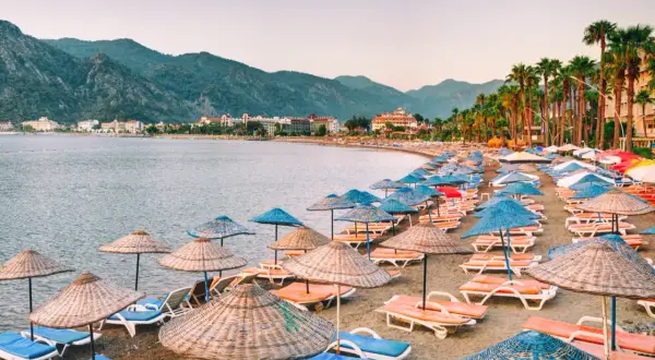 Plaża w Marmaris z rzędami leżaków i parasoli, idealne miejsce na relaks. W tle góry i hotele.