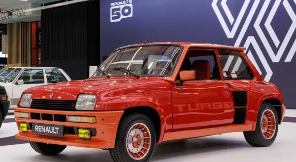 Czerwony Renault 5 Turbo z lat 80. błyszczy na wystawie. Charakterystyczne logo "TURBO" na drzwiach i pomarańczowe akcenty podkreślają jego sportowy charakter.
