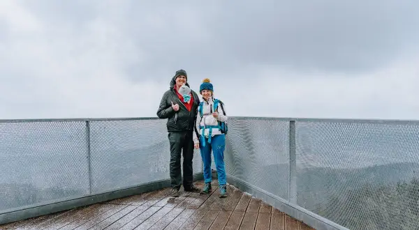 Para z dzieckiem na rękach i druga osoba na tarasie widokowym. Widać, że trójgarb ile się wchodzi, jest wspaniałym miejscem na rodzinne wycieczki.