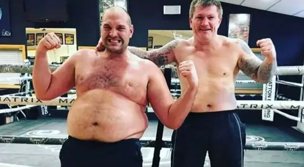 Tyson Fury's build is showcased as he poses shirtless with Ricky Hatton in a boxing ring, both flexing.