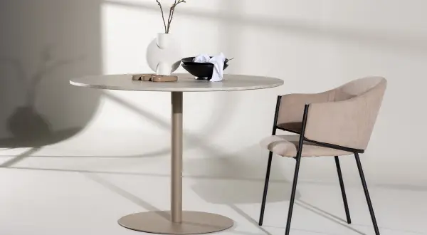 Runt matbord inspiration med en modern stol. En vas med kvistar och skålar på bordet.