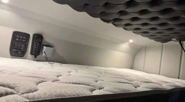 Confortable couchette camion americain avec matelas moelleux et commandes à portée de main.