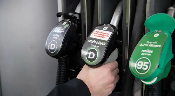 Hand håller bensinpump för miles BENSIN 95, ett alternativ till blyfri bensin. Dieselpump syns också.
