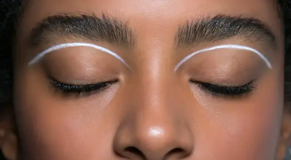Oczy z makijażem w stylu cut crease, podkreślone białymi liniami nad powiekami.