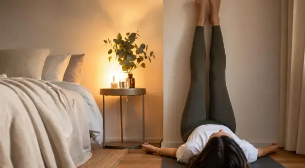 Donna in leggings esegue la posizione yoga con le gambe al muro, un esercizio che aiuta a sentirsi più leggeri e a dimagrire.