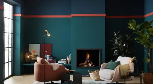 Moderne Wohnzimmer-farbgestaltung wand mit petrol, dunkelblau und korallenroten Akzenten. Gemütliche Sessel und Kamin sorgen für Wohlfühlatmosphäre.