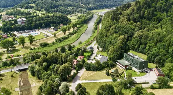 Malowniczy widok na Muszynę z rzeką i lasami. W oddali widać kompleks budynków, w tym sanatorium Revita.