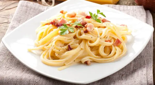 Pyszne spaghetti carbonara, przygotowane według oryginalnego przepisu, z chrupiącym boczkiem i świeżą natką pietruszki.