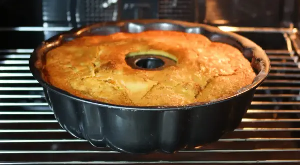 Bizcocho de manzana y naranja recién horneado en su molde, con un dorado perfecto. ¡Huele delicioso!