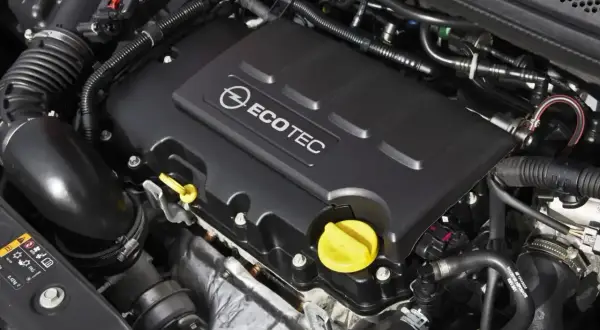 Silnik Ecotec w Oplu Astra J 1.4 Turbo. Widoczne elementy układu dolotowego i osłona silnika z logo.