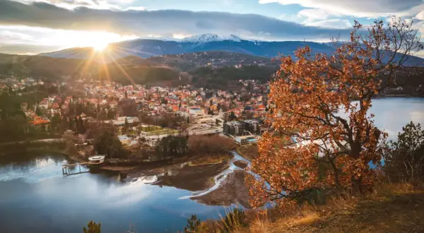 Widok na miasteczko nad jeziorem, góry w tle. Idealne miejsce, gdzie na wakacje w sierpniu, choć liście drzew już brązowe.