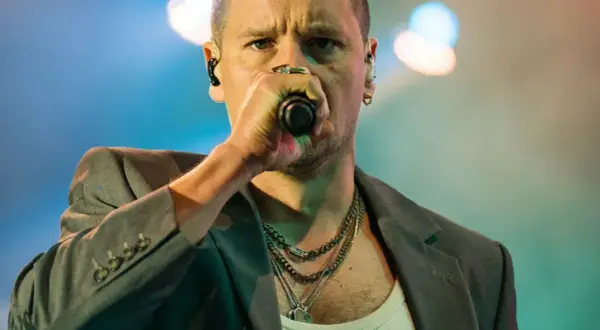 Krzysztof Zalewski śpiewa "Annuszka", w szarym garniturze i z łańcuchami na szyi.