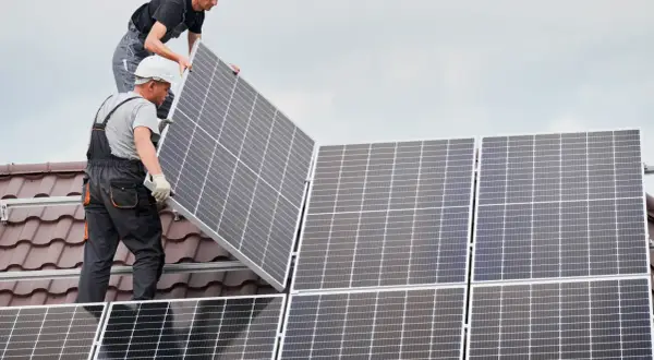 Instaladores colocan placas solares en un tejado, asegurando el anclaje para la energía limpia.