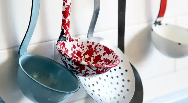 Utensili da cucina nomi: mestoli colorati e forati appesi al muro, pronti per preparare gustose ricette.