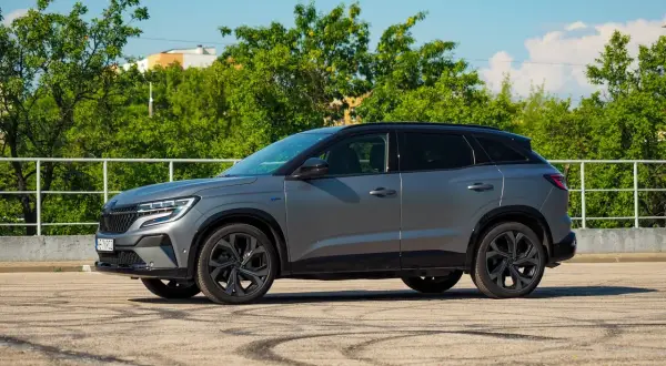 Szary Renault Austral na tle zieleni. Wiele osób szuka **Renault Austral opinie** przed zakupem.