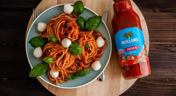 Pyszne spaghetti z kulkami mozzarelli i bazylią, obok butelka passaty pomidorowej Włocławek. Idealny składnik do sosu.