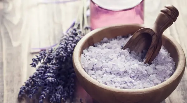 Lavendel badesalz selber machen: Eine Holzschale mit duftendem Lavendelsalz und ein Bündel frischer Lavendelblüten.