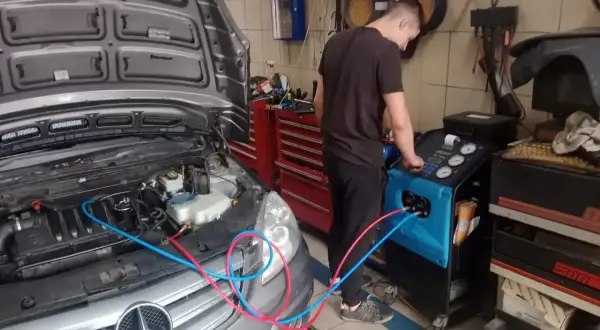 Mechanik wykonuje ozonowanie klimatyzacji w samochodzie Mercedes. Urządzenie do ozonowania podłączone jest do układu.