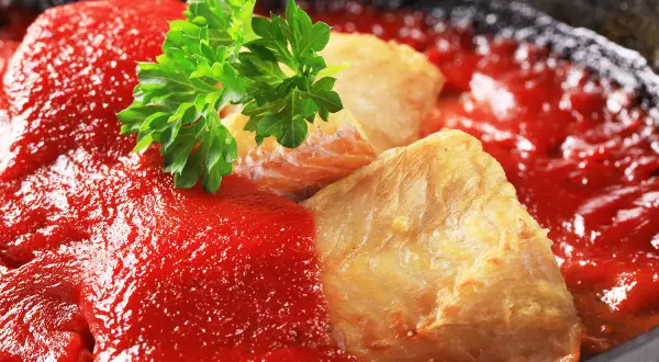 Délicieuse lotte recette en sauce tomate, garnie de persil frais. Un plat savoureux prêt à être dégusté.