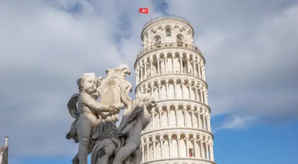 Die Torre de Pisa, ein schiefer Turm, ragt hinter einer barocken Skulptur auf.
