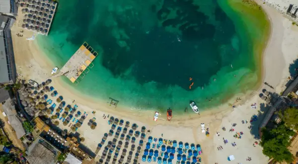 Widok z lotu ptaka na turkusowe morze i piaszczyste plaże Albanii, z rzędami leżaków i parasoli, idealne na wakacje.