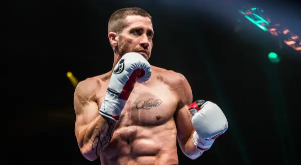 A boxer, possibly Jake Gyllenhaal, in an orthodox stance, ready to fight. His intense gaze suggests a southpaw opponent.