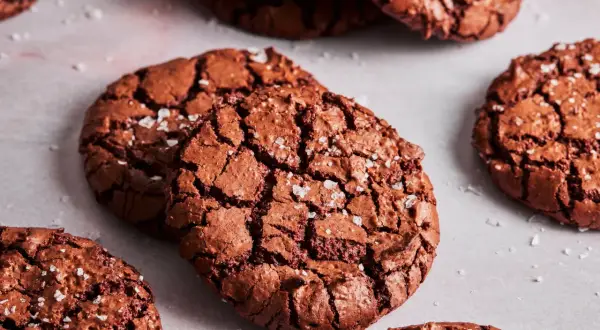 Knusprige brownie cookies mit Meersalzflocken, die auf einer hellen Oberfläche liegen.