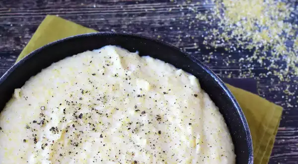 Pyszna, kremowa polenta z mąki kukurydzianej, doprawiona świeżo mielonym pieprzem, gotowa do podania.