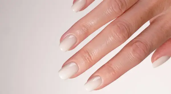 Mano con unghie sposa eleganti, laccate di un bianco perla, perfette per il giorno più bello.