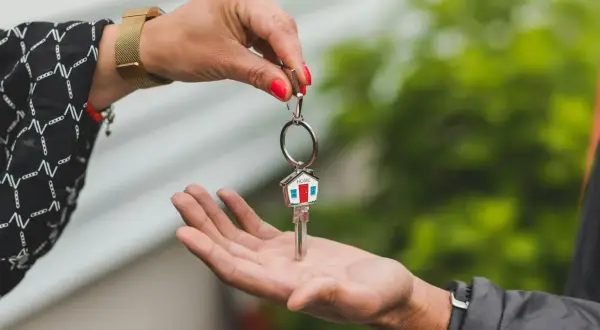 Una mano entrega una llave con un llavero de casa, simbolizando la permuta de viviendas entre particulares.