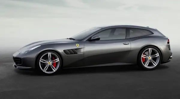 Szary Ferrari FF, sportowe kombi z charakterystycznymi wlotami powietrza i czerwonymi zaciskami hamulcowymi, prezentuje się na tle mglistego nieba.