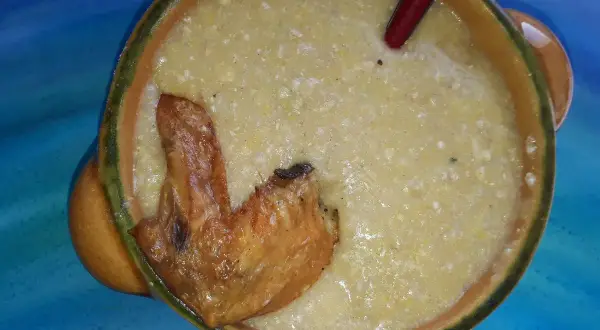 Herzhafte polenta taragna mit einem knusprigen Hähnchenflügel in einer rustikalen Schüssel.