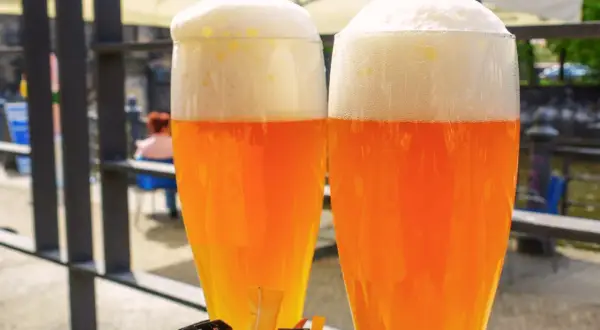 Due bicchieri di hefeweizen birra dorata con schiuma bianca e soffice, pronti per essere gustati all'aperto.