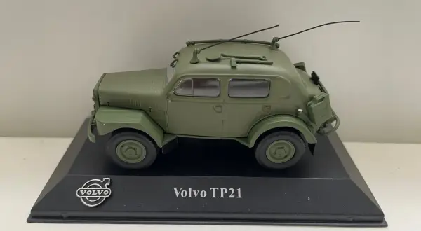 Modell av en grön Volvo TP21 "Sugga" med antenner och takräcke, monterad på en svart piedestal.