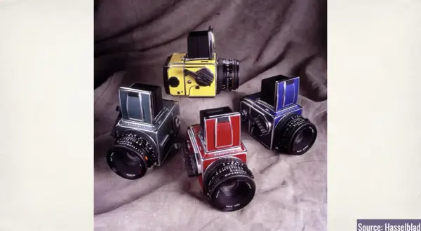 A collection of vintage Hasselblad 500c cameras in various colors: yellow, green, red, and blue.
