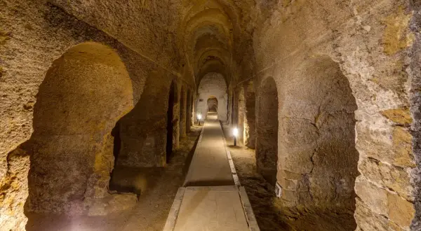 Corridoio sotterraneo scavato nella roccia a Camerano, Ancona, con illuminazione soffusa che crea un'atmosfera suggestiva.