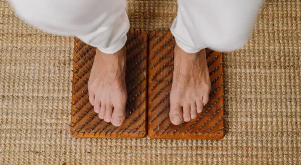 Voeten staan op spijkermat, een oefening voor balans en ontspanning.