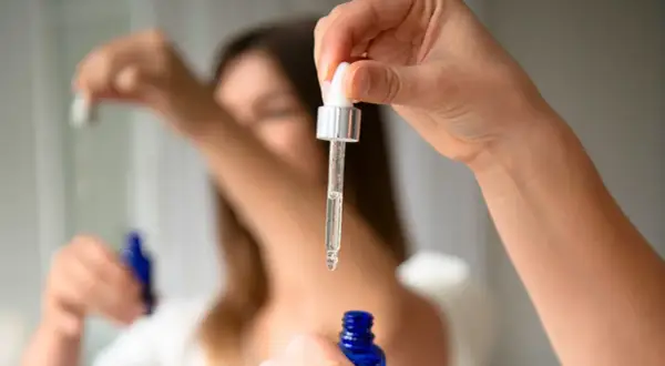 Kropla serum z butylen glicolem spada z pipety do niebieskiej buteleczki.