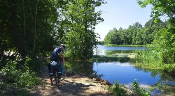 Rowerzysta odpoczywa nad jeziorem, ciesząc się pięknymi trasami rowerowymi w Olsztynie.