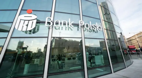 Logo PKO Bank Polski na szklanej fasadzie. W środku wnętrze banku, gdzie można założyć pko bp lokaty.