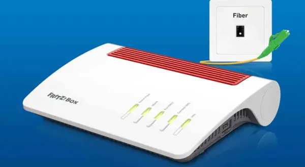 Biały router FRITZ!Box z czerwonymi wstawkami i diodami LED, obok gniazdka Fiber z podłączonym kablem światłowodowym.
