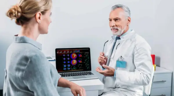 Arzt erklärt Patientin die Ergebnisse einer Mibi-Szintigraphie und bespricht mögliche Risiken.