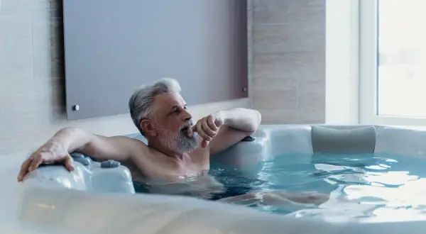 Starszy mężczyzna relaksuje się w jacuzzi. Czysta woda i odpowiednia chemia do jacuzzi zapewniają mu komfort.